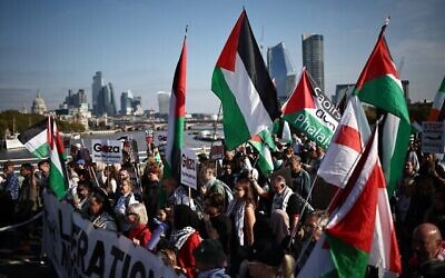 Des manifestants anti-Israël brandissant des pancartes et agitant des drapeaux, dans le centre-ville de Londres, le 11 octobre 2025. (Crédit : Henry Nicholls/AFP)