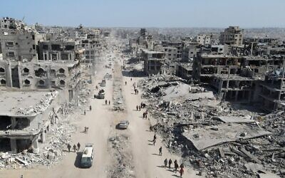 Sur cette vue aérienne, des personnes marchent au milieu des décombres dans Gaza-City, au nord de l'enclave côtière, le 11 octobre 2025 (Crédit : AFP).