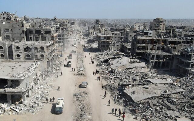 Sur cette vue aérienne, des personnes marchent au milieu des décombres dans Gaza-City, au nord de l'enclave côtière, le 11 octobre 2025 (Crédit : AFP).