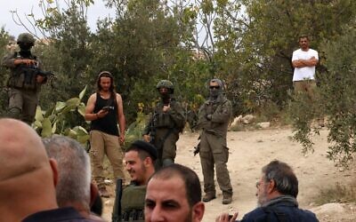 Illustration : Des soldats et des résidents d'implantations israéliens, dans le village d'Edna, au nord de Hébron, en Cisjordanie, pendant la saison de la récolte des olives, le 12 octobre 2025. (Crédit : Hazem Bader/AFP)