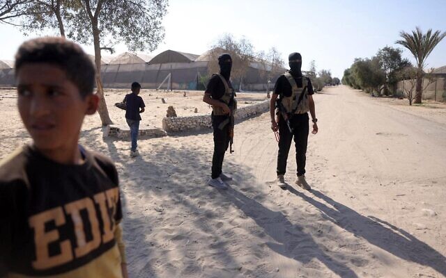 Des membres de la branche militaire du Hamas montent la garde avant de remettre les otages, le 13 octobre 2025. (Crédit : Bashar TALEB / AFP)