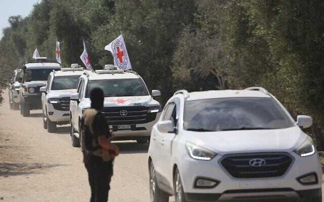 Un homme armé du Hamas regarde depuis le bord de la route les véhicules du Comité international de la Croix-Rouge (CICR) partir avec le deuxième groupe d'otages israéliens libérés par le Hamas à Deir el-Balah, dans le centre de la bande de Gaza, le 13 octobre 2025. (Crédit : Bashar TALEB / AFP)