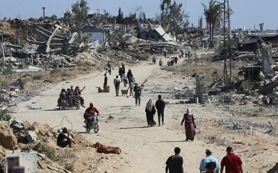 Des Gazaouis déplacés passant devant des bâtiments détruits alors qu'ils rentrent chez eux dans la région d'al-Zahra, au nord du camp de réfugiés de Nuseirat, dans le centre de la bande de Gaza, le 14 octobre 2025. (Crédit : Eyad Baba/AFP)