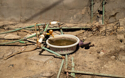 Une cuve placée sous un robinet relié à un réseau de tuyaux puisant l'eau de différentes sources dans le village d'al-Mashab, situé dans les marais au nord de Bassorah, dans le sud de l'Irak, le 13 septembre 2025.  (Crédit : Hussein FALEH / AFP)