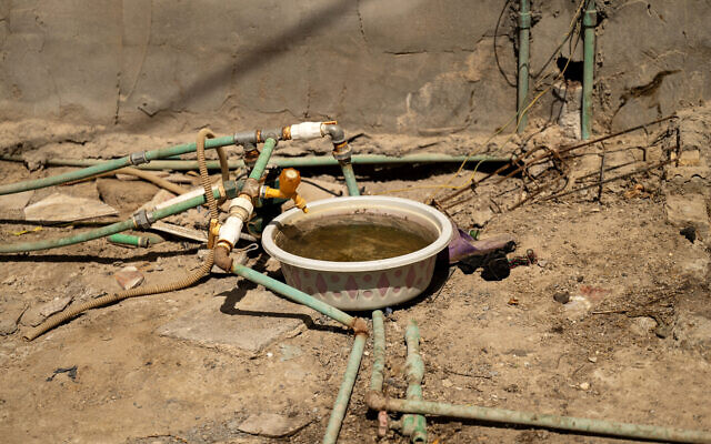 Une cuve placée sous un robinet relié à un réseau de tuyaux puisant l'eau de différentes sources dans le village d'al-Mashab, situé dans les marais au nord de Bassorah, dans le sud de l'Irak, le 13 septembre 2025. (Crédit : Hussein FALEH / AFP) Une cuve placée sous un robinet relié à un réseau de tuyaux puisant l'eau de différentes sources dans le village d'al-Mashab, situé dans les marais au nord de Bassorah, dans le sud de l'Irak, le 13 septembre 2025. (Crédit : Hussein FALEH / AFP)