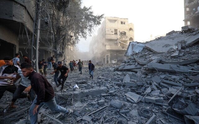 Des gens courent pour se mettre à l'abri après une frappe israélienne qui a visé un bâtiment dans le camp de Bureij, dans le centre de la bande de Gaza, le 19 octobre 2025. (Crédit : Eyad BABA / AFP) Des gens courent pour se mettre à l'abri après une frappe israélienne qui a visé un bâtiment dans le camp de Bureij, dans le centre de la bande de Gaza, le 19 octobre 2025. (Crédit : Eyad BABA / AFP)
