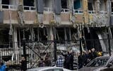 Des habitants marchent près d'un centre d'affaires endommagé à la suite d'une attaque de drone à Kiev, le 23 octobre 2025, dans le contexte de l'invasion russe en Ukraine. (Crédit : Tetiana DZHAFAROVA / AFP)