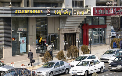 Des Iraniens passent devant une succursale de la banque Ayandeh (à gauche) dans la capitale Téhéran, le 14 janvier 2017. (Crédit :: ATTA KENARE / AFP