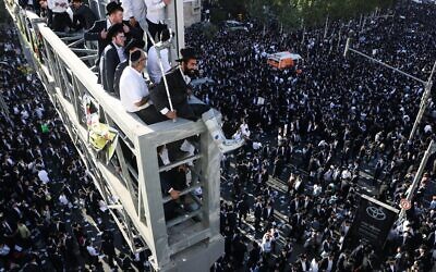 Des ultra-orthodoxes assis sur un pont surplombant la foule lors d’une manifestation organisée par des ultra-orthodoxes contre la conscription dans l’armée israélienne, à Jérusalem, le 30 octobre 2025. (Crédit : Ahmad Gharabli/AFP)
