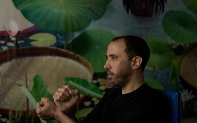 L'otage israélien libéré Tal Shoham, qui était détenu par des terroristes du Hamas dans la bande de Gaza, montre comment ses ravisseurs l'ont menotté, à Tel Aviv, le 22 avril 2025. (Crédit : AP Photo/Maya Alleruzzo)