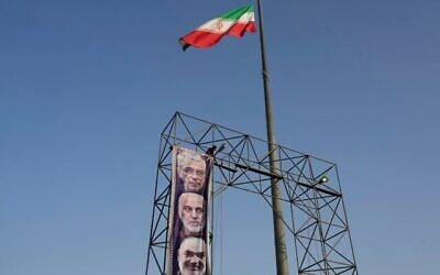 Un ouvrier accroche une banderole de portraits des défunts commandants des forces armées iraniennes, le général Mohammad Hossein Bagheri, en haut, le général Gholamali Rashid, au centre, et le général Hossein Salami, tués par des frappes israéliennes en juin dernier, sur la place Baharestan de Téhéran, le 22 septembre 2025. (Crédit : AP Photo/Vahid Salemi)