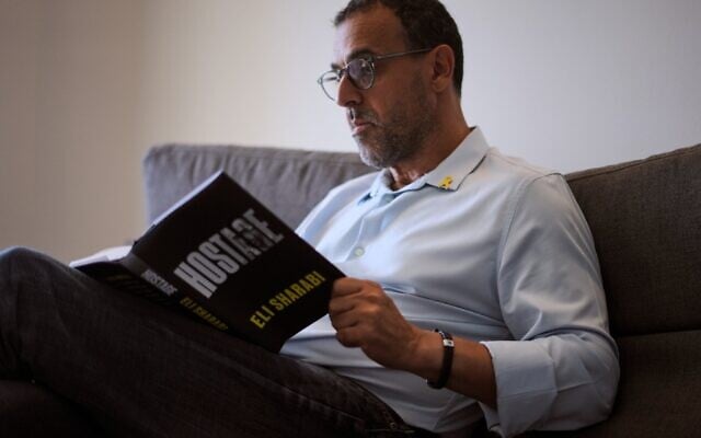 Eli Sharabi, qui a été enlevé lors de l'attaque du Hamas contre Israël le 7 octobre 2023 et retenu en otage par le Hamas pendant 16 mois, pose avec son nouveau livre « Hostage » pour une photo à Herzliya, le 18 septembre 2025. (Crédit : AP Photo/Ariel Schalit)