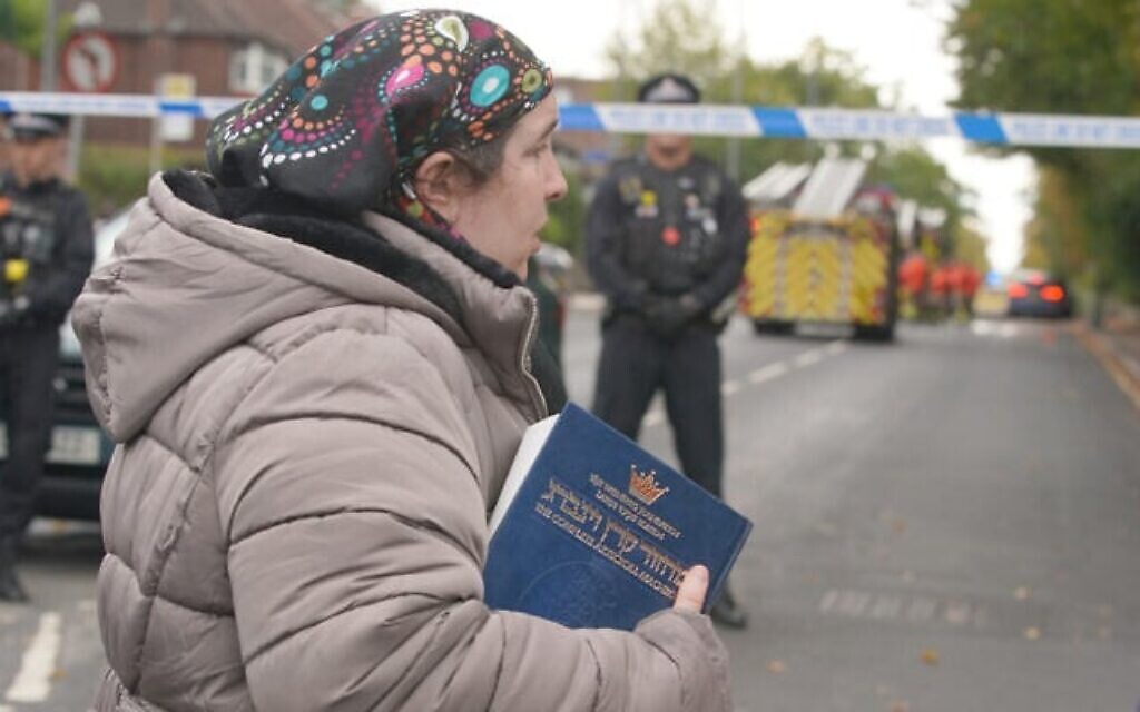 Une femme tient un livre religieux juif alors qu'elle marche près du lieu d'une attaque au couteau à la synagogue Heaton Park Hebrew Congregation, à Crumpsall, Manchester, en Angleterre, le 2 octobre 2025. (Crédit : AP Photo/Ian Hodgson)