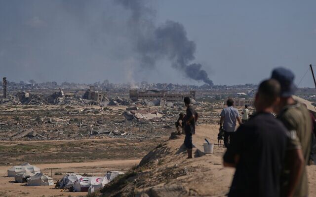 Des Palestiniens déplacés regardent la fumée s'élever dans le ciel après une frappe militaire israélienne dans la ville de Gaza, vue depuis le centre de la bande de Gaza, le 2 octobre 2025. (Crédit : AP Photo/Abdel Kareem Hana) Des Palestiniens déplacés regardent la fumée s'élever dans le ciel après une frappe militaire israélienne dans la ville de Gaza, vue depuis le centre de la bande de Gaza, le 2 octobre 2025. (Crédit : AP Photo/Abdel Kareem Hana)