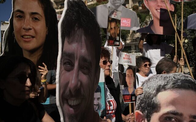 Des proches et des sympathisants des otages israéliens détenus par le Hamas dans la bande de Gaza brandissent des affiches avec les portraits de leurs proches lors d'une manifestation exigeant leur libération immédiate et appelant à un cessez-le-feu, à Jérusalem, le 7 octobre 2025. (Crédit : AP Photo/Leo Correa)