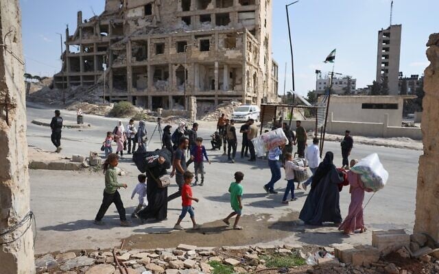 Des habitants passant devant un poste de contrôle des forces de sécurité alors qu'ils quittent les quartiers de Sheikh Maqsoud et Achrafieh à Alep, en Syrie, le 7 octobre 2025, à la suite d'affrontements nocturnes entre les troupes gouvernementales syriennes et les Forces démocratiques syriennes dirigées par les Kurdes. (Crédit : Omar Albam/AP Photo) Des habitants passant devant un poste de contrôle des forces de sécurité alors qu'ils quittent les quartiers de Sheikh Maqsoud et Achrafieh à Alep, en Syrie, le 7 octobre 2025, à la suite d'affrontements nocturnes entre les troupes gouvernementales syriennes et les Forces démocratiques syriennes dirigées par les Kurdes. (Crédit : Omar Albam/AP Photo)
