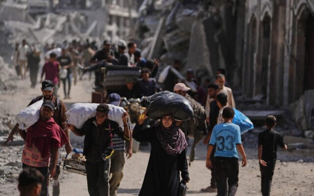 Des Palestiniens évacués passent avec leurs quelques possessions devant des bâtiments détruits sur le chemin du retour, à Khan Younès, dans le sud de la bande de Gaza, le 10 octobre 2025. (Crédit : AP Photo/Jehad Alshrafi)