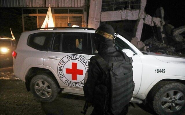 Un terroriste vêtu d'un uniforme des Brigades Ezzedine al-Qassam, la branche armée du Hamas, montant la garde alors que des véhicules de la Croix-Rouge transportant prétendument les cercueils contenant les corps de quatre otages décédés quittent un entrepôt pour Israël, à Gaza-City, le 14 octobre 2025. (Crédit : Yousef al-Zanoun/AP)