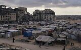 Un campement de tentes pour les Palestiniens déplacés se trouve à côté de maisons et de bâtiments détruits à Khan Younis, dans la bande de Gaza, le 18 octobre 2025. (Crédit : AP Photo/Jehad Alshrafi)