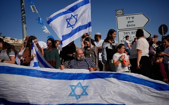 Des personnes se rassemblent pour accueillir l'otage israélien Avinatan Or, récemment libéré après avoir été retenu captif par le Hamas à Gaza, alors qu'il rentre de l'hôpital vers son domicile dans l'implantation de Shilo, en Cisjordanie, le 21 octobre 2025. (Crédit : AP/Ohad Zwigenberg) Des personnes se rassemblent pour accueillir l'otage israélien Avinatan Or, récemment libéré après avoir été retenu captif par le Hamas à Gaza, alors qu'il rentre de l'hôpital vers son domicile dans l'implantation de Shilo, en Cisjordanie, le 21 octobre 2025. (Crédit : AP/Ohad Zwigenberg)
