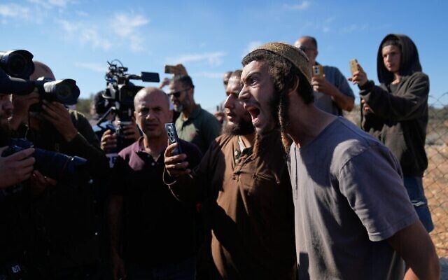 Des résidents d'implantations israéliens prennent des photos de militants étrangers et d'agriculteurs alors qu'ils tentent de perturber la récolte des olives par des agriculteurs palestiniens, dans la ville de Silwad, en Cisjordanie, le 29 octobre 2025. (Crédit : Nasser Nasser/AP)