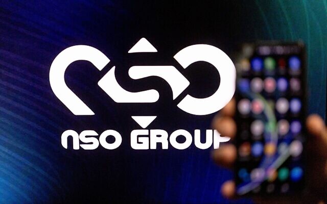 Un homme tient son téléphone avec le logo NSO GROUP sur un écran d'ordinateur en arrière-plan, à Jérusalem, le 7 février 2022. (Crédit : Yonatan Sindel/Flash90) Un homme tient son téléphone avec le logo NSO GROUP sur un écran d'ordinateur en arrière-plan, à Jérusalem, le 7 février 2022. (Crédit : Yonatan Sindel/Flash90)