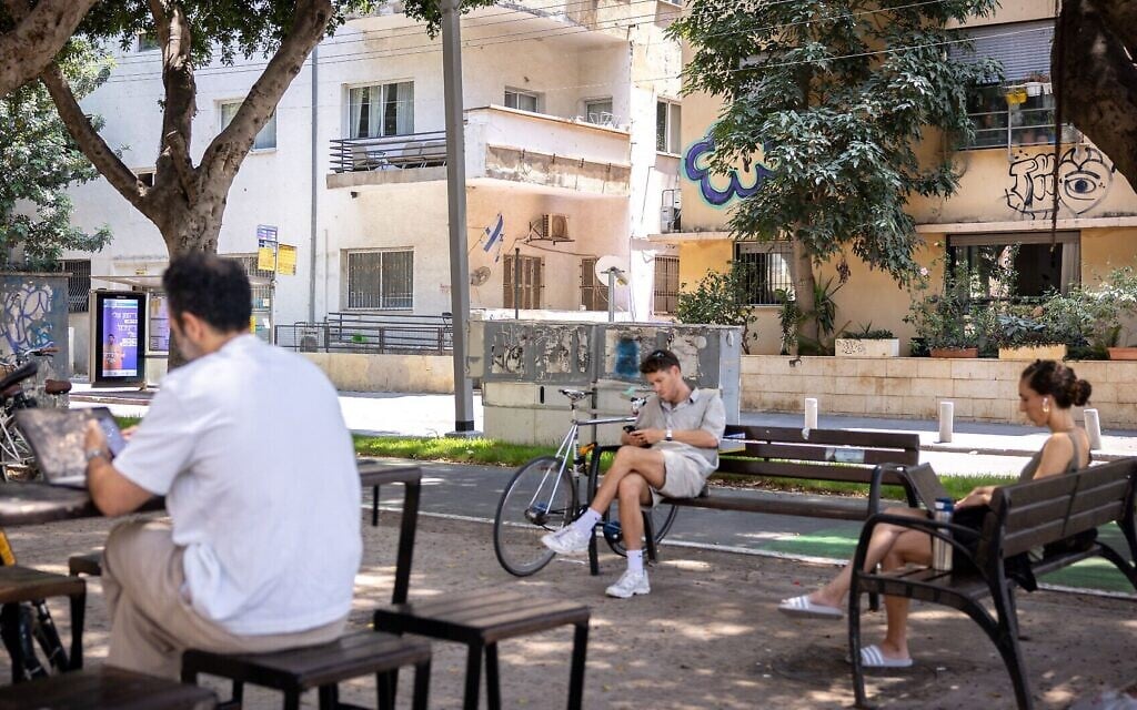 Illustration : Des gens regardent leurs appareils électroniques tout en se relaxant à Tel Aviv, le 4 juin 2025. (Crédit : Miriam Alster/FLASH90)