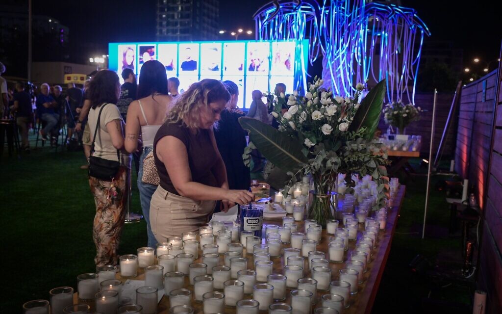 Une femme allume des bougies en hommage aux victimes de l'attentat du 7 octobre lors d'un événement organisé à Tel Aviv le 5 octobre 2025. (Crédit : Avshalom Sassoni/Flash90)