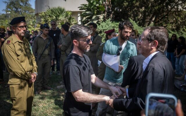 L'ex-otage David Cunio (à gauche) s'adressant au président Isaac Herzog lors des funérailles de l'otage assassiné Tamir Adar au kibboutz Nir Oz, le 23 octobre 2025, tandis que son compagnon d'infortune Sagui Dekel-Chen se tient à l'arrière-plan. (Crédit : Chaïm Goldberg/Flash90)
