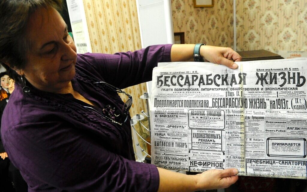La bibliothécaire Olga Sivak montrant une édition datant de 1913 du journal Bessarabian Life, au Musée juif de Moldavie, à Chișinău. (Crédit : Larry Luxner/JTA)
