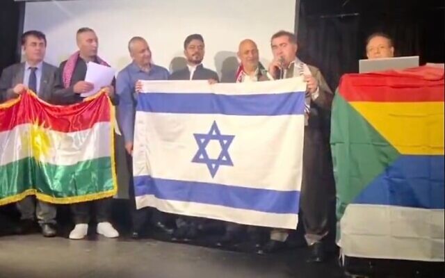 Les participants à la conférence « L’avenir des minorités au Moyen-Orient » à Tel Aviv brandissent les drapeaux kurde, israélien et druze, le 27 octobre 2025. (Crédit : Capture d’écran/X ; utilisée conformément à la clause 27a de la loi sur le droit d’auteur)