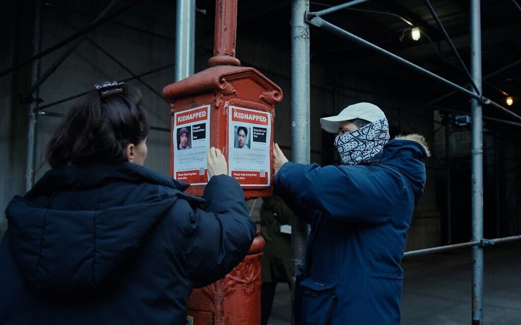 Les artistes et concepteurs de la campagne "KIDNAPPED" lancée après le 7 octobre, Nitzan Mintz et Dede Bandaid, accrochent des affiches dans le film de Nim Shapira "TORN : The Israel-Palestine Poster War on NYC Streets" (Crédit : Eyal Bau Cohen).