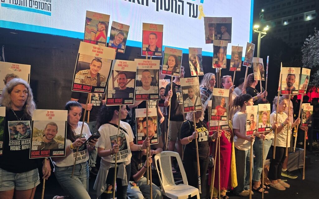 Les familles des otages détenus à Gaza sur la scène de la place des Otages à Tel-Aviv le 11 octobre 2025, brandissant des affiches de leurs proches, qui devraient rentrer chez eux dans les deux prochains jours. (Crédit : Shai Hazan / Mouvement de protestation pro-démocratie)
