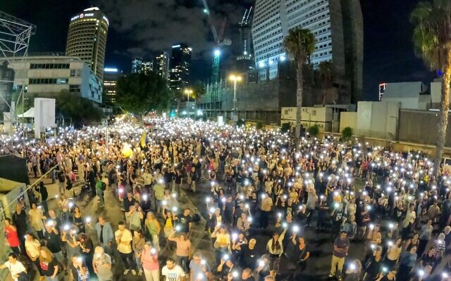 Les personnes rassemblées près de la place des Otages, à Tel Aviv, allument leurs téléphones portables pendant l'hymne national israélien, la Hatikva, à la fin d'une manifestation réclamant la restitution des corps des otages tués à Gaza, le 18 octobre 2025. (Crédit : Gilad Furst / Mouvement de protestation pour la démocratie) Les personnes rassemblées près de la place des Otages, à Tel Aviv, allument leurs téléphones portables pendant l'hymne national israélien, la Hatikva, à la fin d'une manifestation réclamant la restitution des corps des otages tués à Gaza, le 18 octobre 2025. (Crédit : Gilad Furst / Mouvement de protestation pour la démocratie)