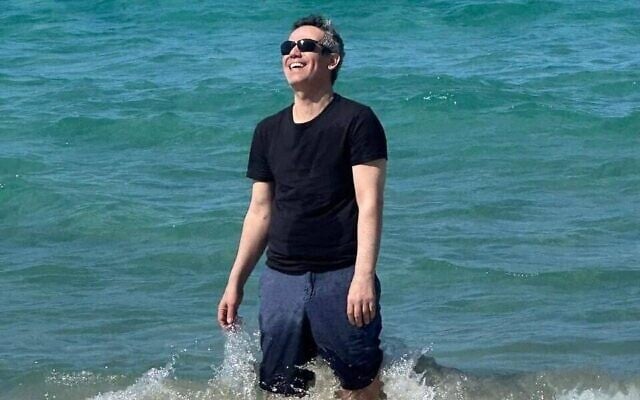 Omri Miran photographié à la plage, avec sa femme Lishay et ses deux filles (hors champ), le 17 octobre 2025, peu après sa sortie de l'hôpital et quatre jours après avoir été libéré après plus de deux ans de captivité par le Hamas à Gaza. (Crédit : Via X ; Eli Teichman et Shir Katz)