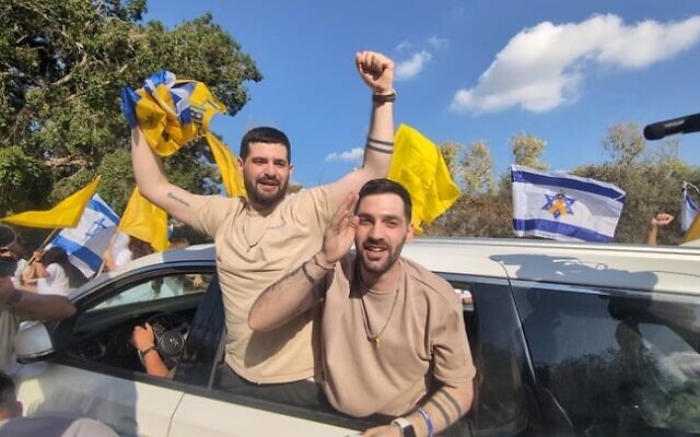Les otages libérés Gal et Ziv Berman saluent la foule en liesse qui les accueille au kibboutz Beit Guvrin le 19 octobre 2025 (Crédit : Tanya Zion-Waldoks/Mouvement israélien de protestation pour la démocratie).