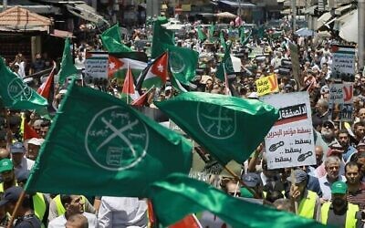 Illustration : Des drapeaux des Frères musulmans, de la Jordanie et d'autres partis politiques sont brandis avec d'autres pancartes dénonçant la conférence économique sur le Moyen-Orient organisée par les États-Unis à Bahreïn, le 21 juin 2019. (Crédit : Khalil Mazraawi/ AFP)