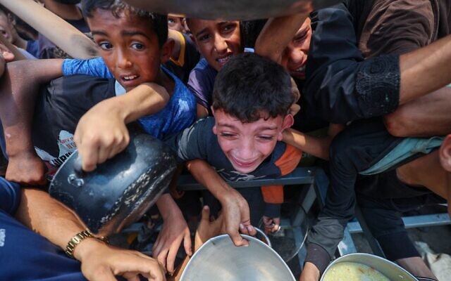 Des enfants palestiniens attendent de la nourriture à un point de distribution à Nuseirat, dans le centre de la bande de Gaza, le 11 juin 2025. (Crédit : Eyad BABA/AFP)