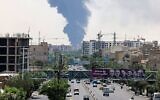 Les portraits des généraux et des scientifiques nucléaires iraniens tués lors de l'attaque israélienne du 13 juin sont affichés au-dessus d'une route, tandis qu'un panache de fumée épaisse et des flammes s'élèvent d'une raffinerie de pétrole dans le sud de Téhéran, après avoir été touchée par une frappe israélienne nocturne, le 15 juin 2025. (Crédit : ATTA KENARE / AFP)