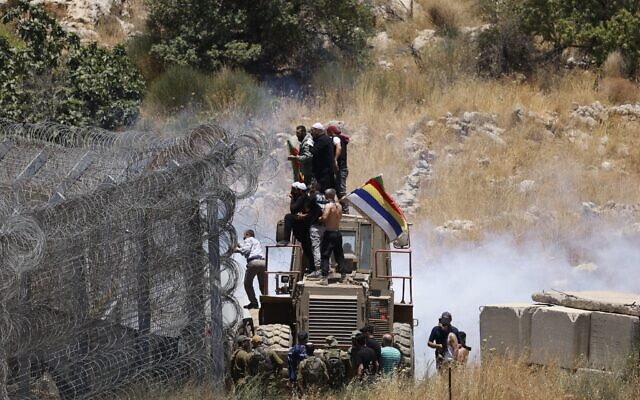 Les soldats israéliens utilisent des gaz lacrymogènes pour disperser la foule alors que des Druzes tentent de franchir la frontière syrienne sur le plateau du Golan, près de Majdal Shams, le 16 juillet 2025. (Crédit : Jalaa MAREY / AFP)