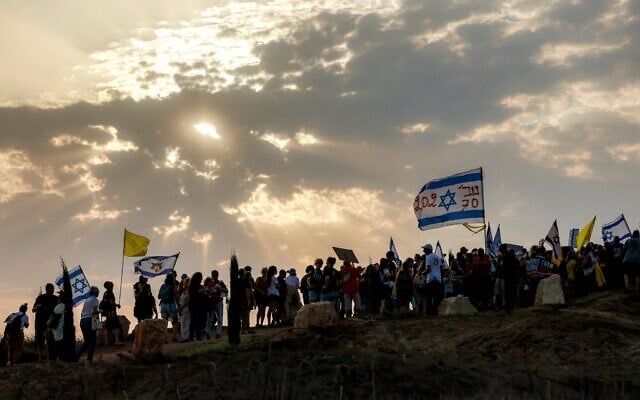 Des personnes défilent avec des drapeaux appelant à la fin de la guerre près du kibboutz Nahal Oz, dans le sud d'Israël, près de la frontière avec la bande de Gaza, le 10 août 2025. (Crédit : Menahem KAHANA / AFP)