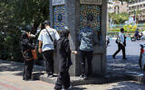 Des Iraniens boivent l'eau d'une fontaine publique dans une rue de Téhéran, le 22 juillet 2025.. (Crédit : AFP)