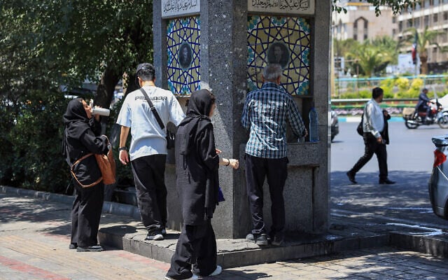 Des Iraniens boivent l'eau d'une fontaine publique dans une rue de Téhéran, le 22 juillet 2025.. (Crédit : AFP) Des Iraniens boivent l'eau d'une fontaine publique dans une rue de Téhéran, le 22 juillet 2025.. (Crédit : AFP)