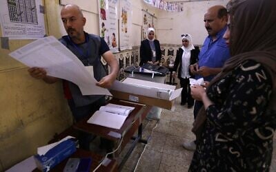 Un responsable électoral irakien remet des bulletins de vote à des électeurs dans un bureau de vote du quartier d'Adhamiya à Bagdad, le 11 novembre 2025, lors des élections législatives irakiennes. (Crédit : AHMAD AL-RUBAYE / AFP) Un responsable électoral irakien remet des bulletins de vote à des électeurs dans un bureau de vote du quartier d'Adhamiya à Bagdad, le 11 novembre 2025, lors des élections législatives irakiennes. (Crédit : AHMAD AL-RUBAYE / AFP)