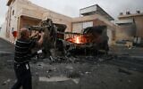 Un Palestinien filmant un camion en feu avec son téléphone portable après une attaque menée par des résidents d'implantations israéliens, dans le village de Beit Lid, à l'est de Tulkarem, en Cisjordanie, le 11 novembre 2025. (Crédit : Jaafar Ashtiyeh/AFP)