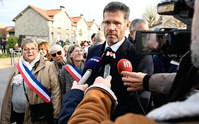 Le préfet de Meuse Xavier Delarue (à droite) répondant à la question d'un journaliste avant une manifestation devant l'église Saint-Jean-Baptiste, où s'est déroulée une cérémonie religieuse « en hommage au maréchal Pétain et à ses soldats » organisée par l'ADMP (Association pour la défense de la mémoire du maréchal Pétain), à Verdun, dans le nord-est de la France, le 15 novembre 2025. (Crédit : Jean-Christophe Verhaegen/AFP)