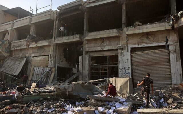 Des Palestiniens inspectent les décombres d'un bâtiment endommagé dans le quartier de Zeitoun à Gaza-City, le 20 novembre 2025. (Crédit : Omar AL-QATTAA / AFP)
