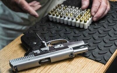 Illustration : un homme s'apprête à charger des balles dans son pistolet semi-automatique 9 mm pour une démonstration de tir dans son stand de tir, le 23 juin 2022, à New York. (Crédit : AP Photo/Bebeto Matthews)