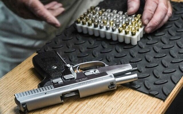 Illustration : un homme s'apprête à charger des balles dans son pistolet semi-automatique 9 mm pour une démonstration de tir dans son stand de tir, le 23 juin 2022, à New York. (Crédit : AP Photo/Bebeto Matthews)