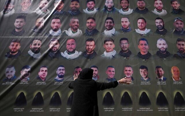 Une femme à côté d'une affiche de yerroristes du Hezbollah lors d’un enterrement collectif dans le sud du Liban, le 28 février 2025. (Crédit : Hassan Ammar/AP)